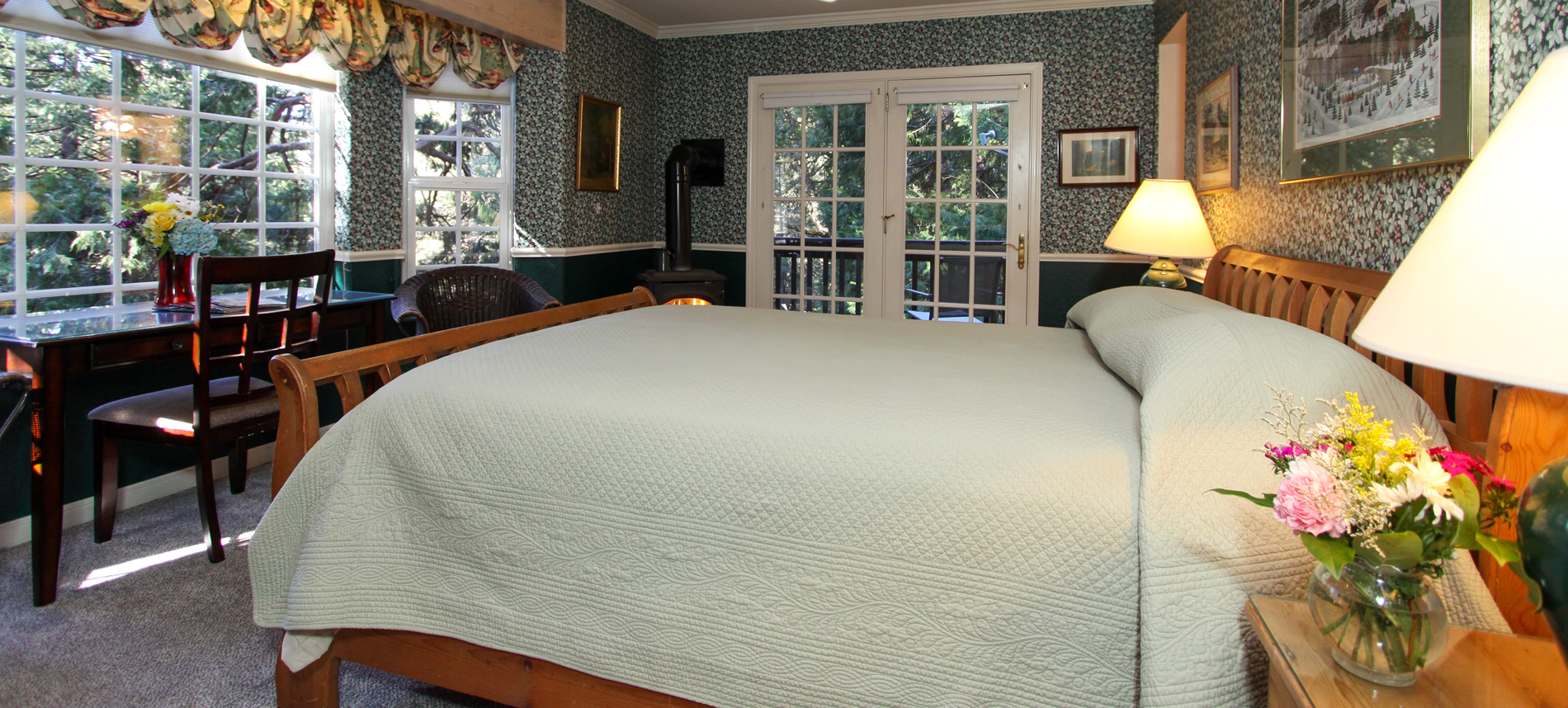 guest room with forest view, bed, desk and firestove